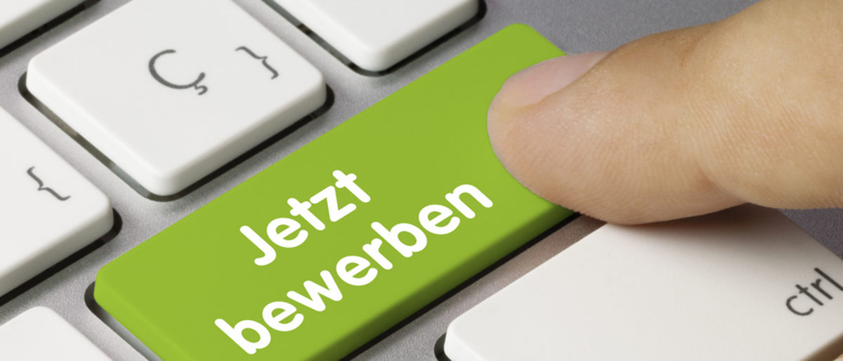 Eine PC-Tastatur auf der eine Taste grün farblich markiert ist. Darauf steht: "Jetzt bewerben". Ein Finger drückt darauf.