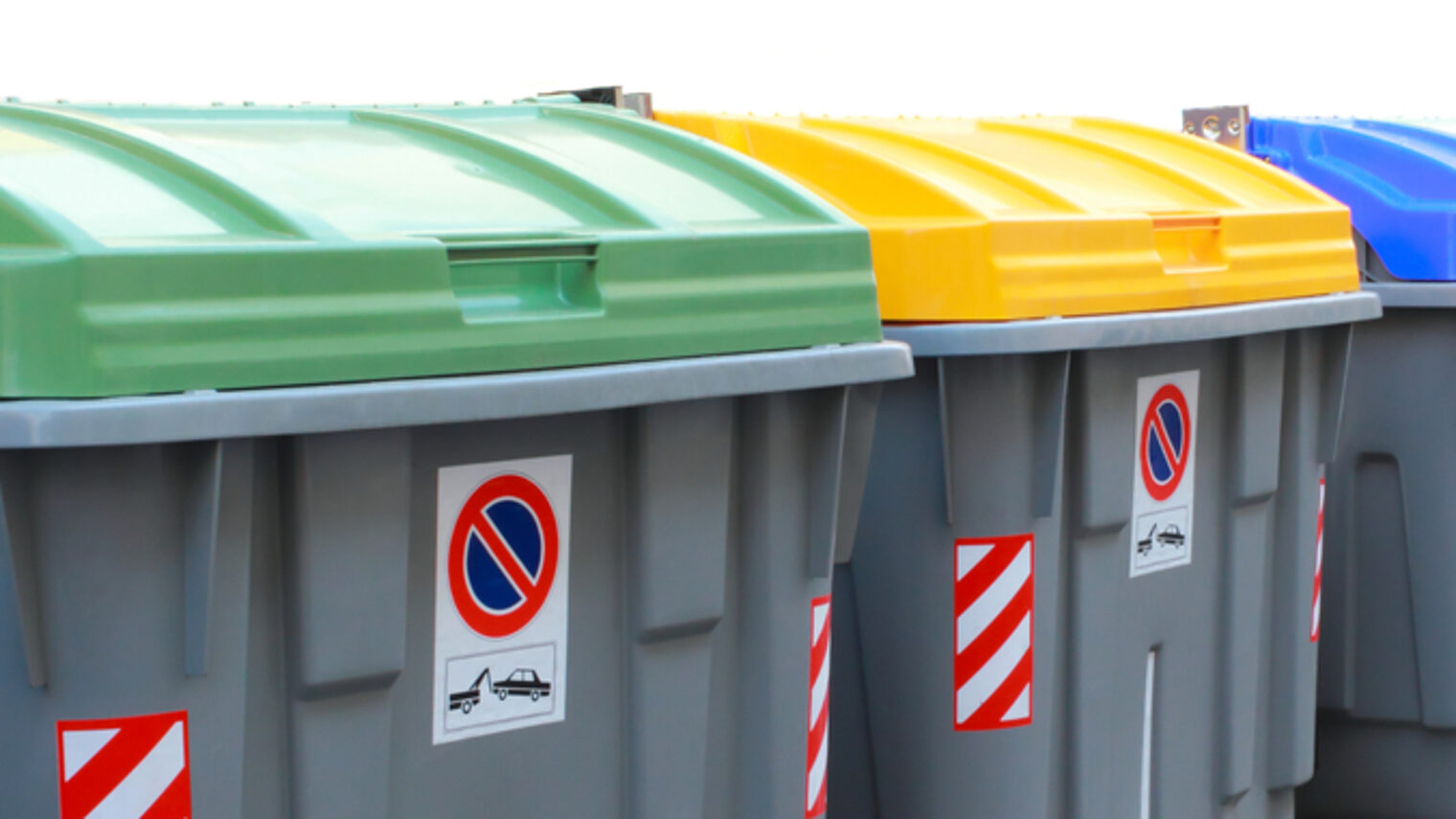 Mehrere große Recycling Müllcontainer mit grünen, gelben und blauen Deckel
