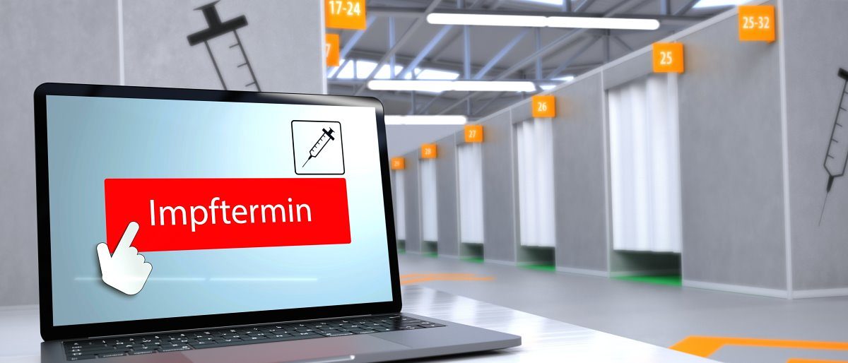 Handwerk fordert mehr Unterstützung für kleine Betriebe bei Impfungen. Im Vordergrund ein Laptop, im Display Schriftzug Impftermin auf roter Fläche. Im Hintergrund nummerierte Kabinen mit Vorhängen