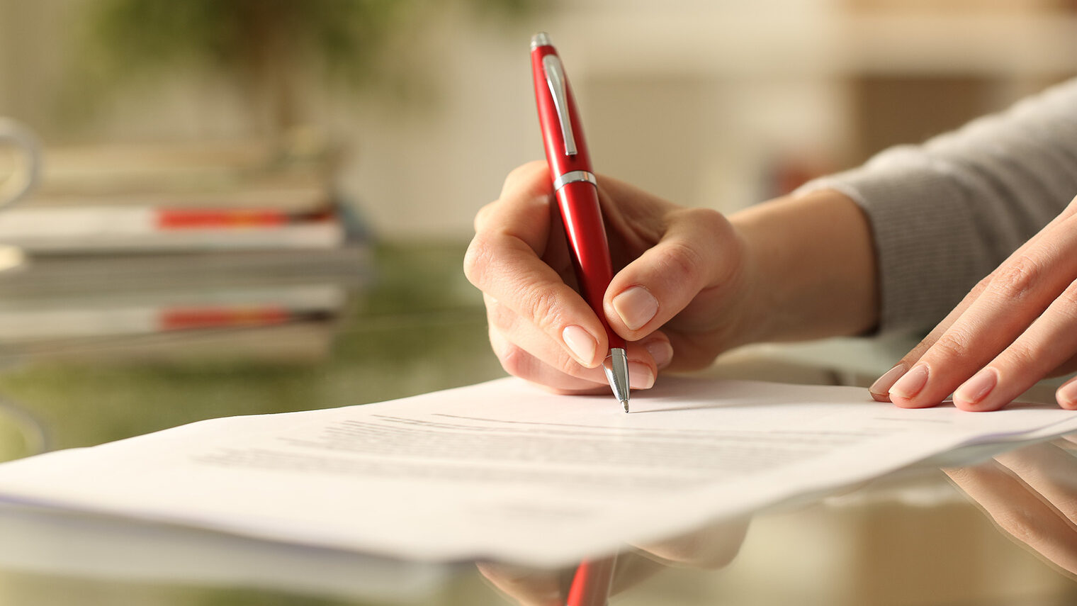 Musterverträge und Downloads Eine Frau unterschreibt ein Dokument.